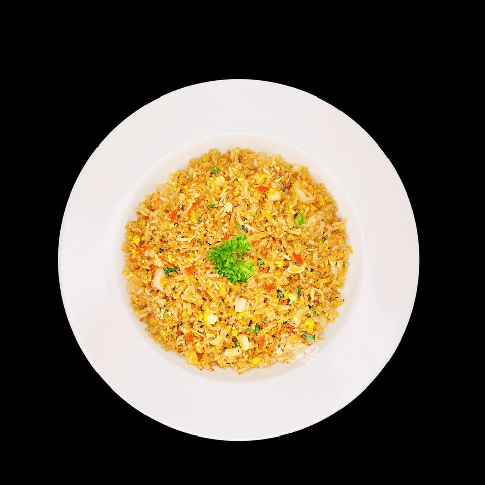 A white plate filled with Vietnamese fried rice, garnished with parsley, against a black background.