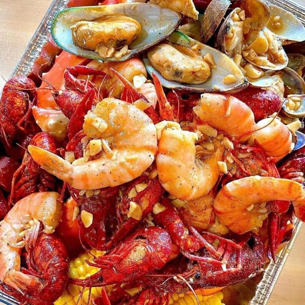 A large platter of Vietnamese-style seafood boil with crawfish, shrimp, mussels, and corn.